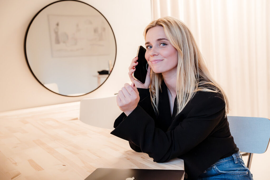 Contentmaker Roos heeft haar mobiel in de hand, en zit klaar voor jouw telefoontje over webteksten laten schrijven.
